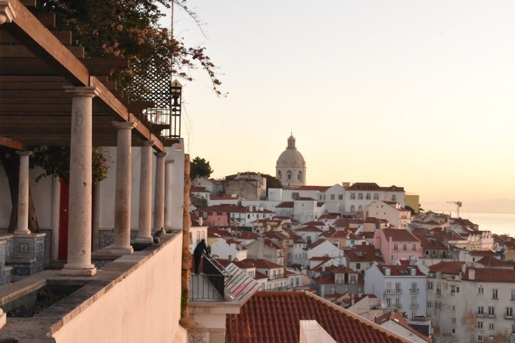 Lisbon rooftops and domed church viewed from a columned miradouro