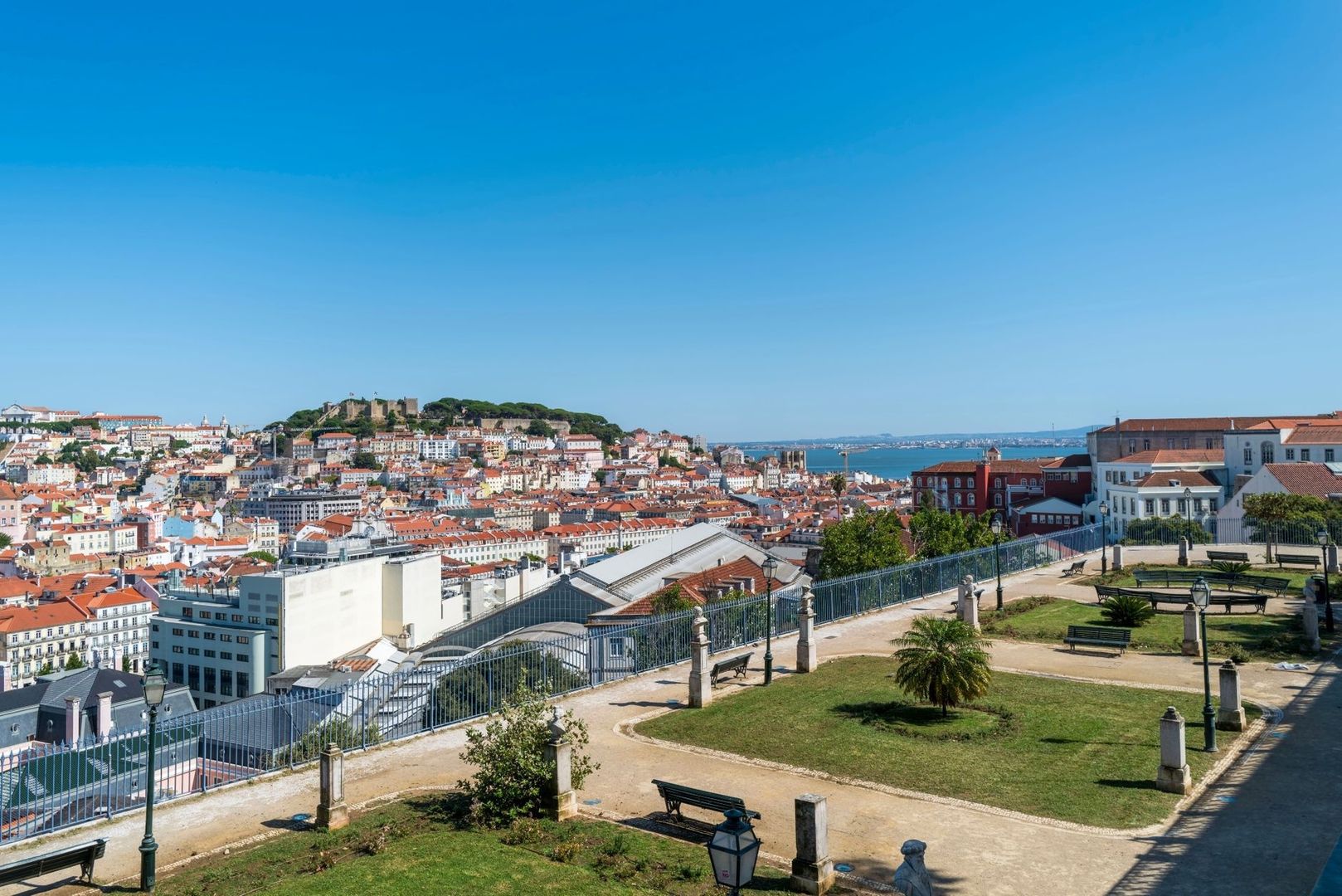 Lisbon rooftops, castle, waterfront, and a landscaped miradouro