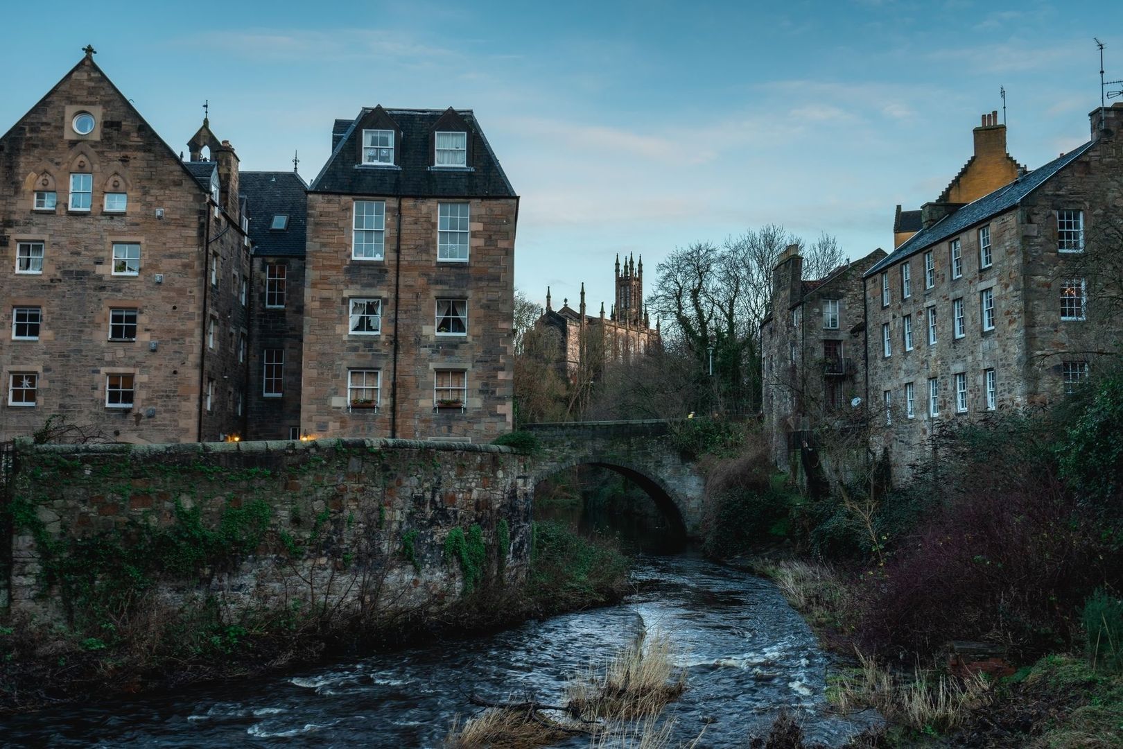 Historic stone buildings and a bridge over a stream in Edinburgh
